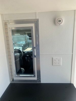 A room with a window and a smoke detector on the wall.