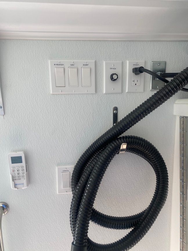 A vacuum hose is hanging on a wall next to a remote control.