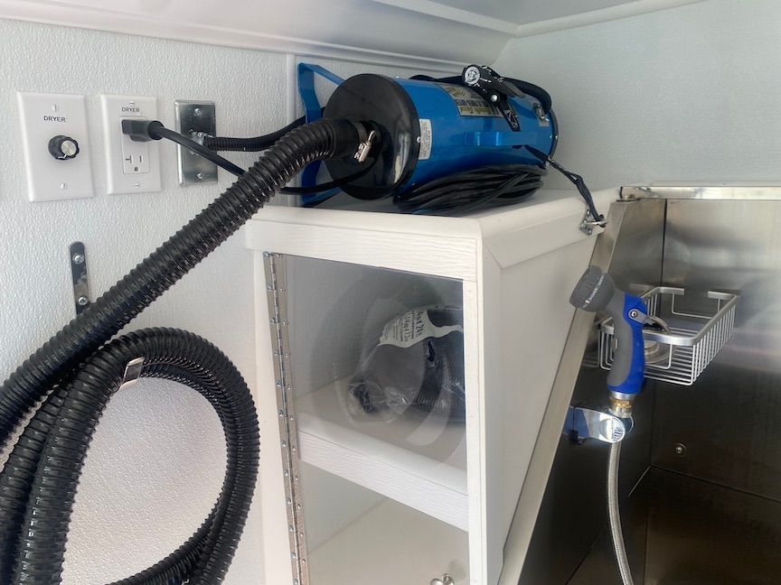 A vacuum cleaner is sitting on top of a shelf next to a sink.