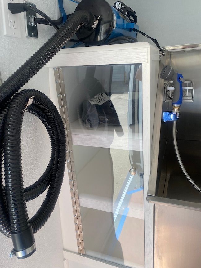 A vacuum hose is attached to a cabinet next to a sink