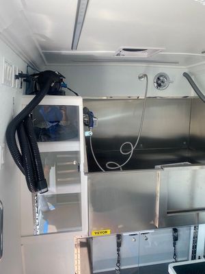 A dog grooming van with a stainless steel sink and shower.
