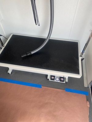 A black and white table with a vacuum hose attached to it.