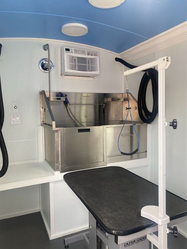 A dog grooming van with a stainless steel sink and a table.