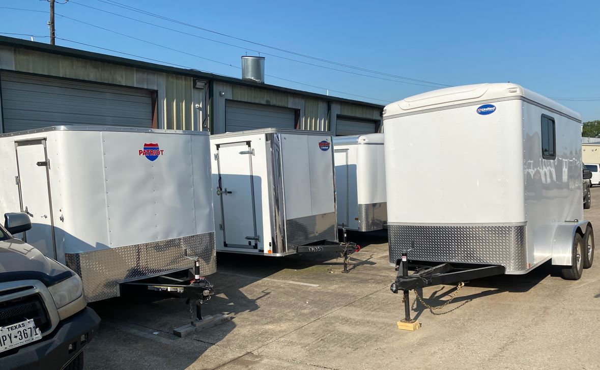 A row of white trailers are parked in a parking lot.
