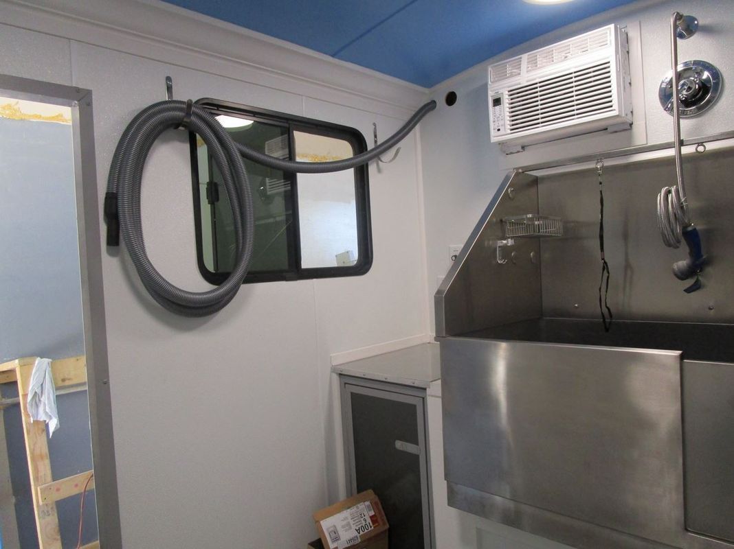 A vacuum hose is attached to a window in a bathroom.