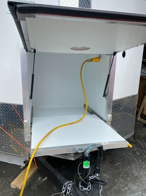 A trailer with the door open and a yellow cord coming out of it.