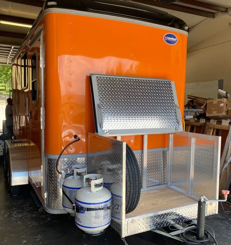 An orange trailer with two propane tanks attached to it