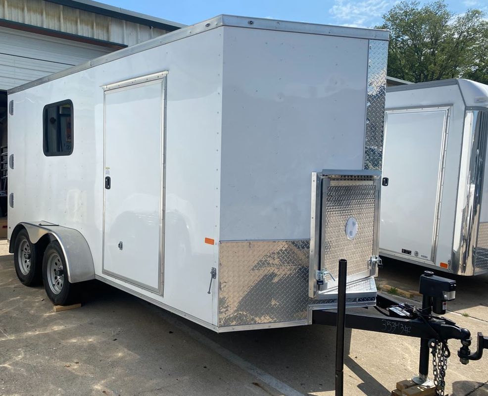 A white trailer is parked in front of a building.