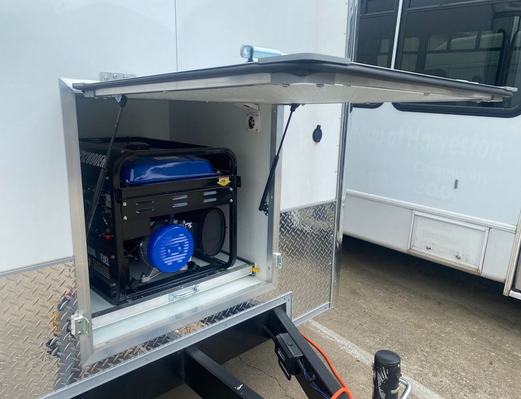 A generator is sitting inside of a trailer with the door open.