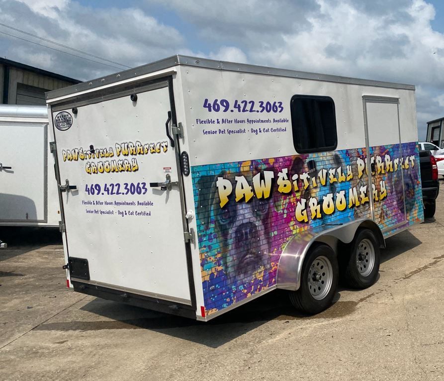 A white trailer with graffiti on it is parked in a parking lot.