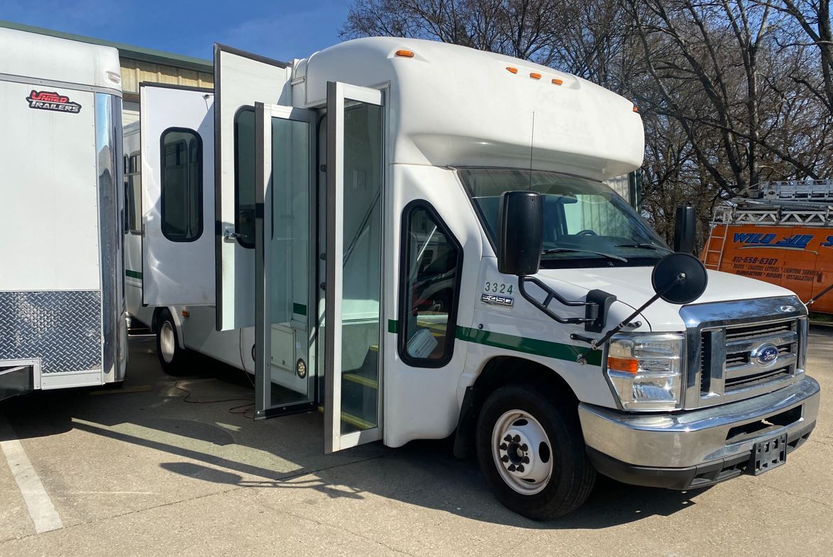A white van with the doors open is parked next to a trailer.