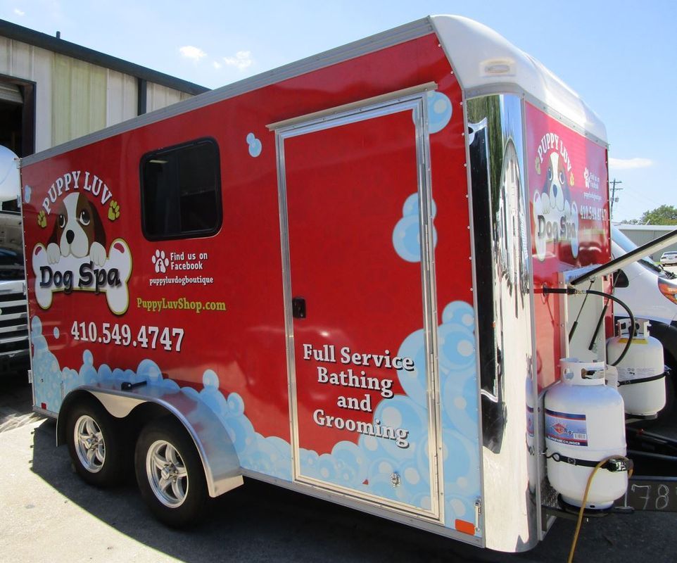 A red trailer that says puppy love dog spa