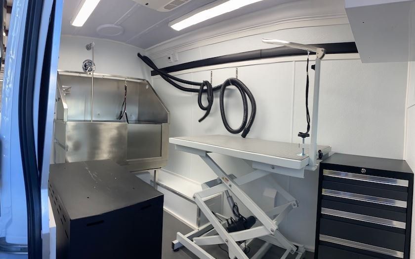 The inside of a dog grooming van with a table and a sink.