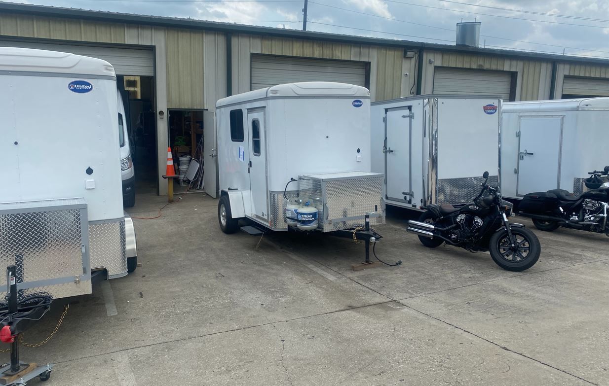 A row of trailers and motorcycles parked in front of a building.