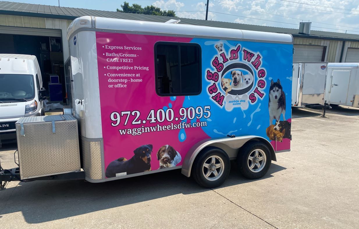 A pink and blue trailer is parked in a parking lot.