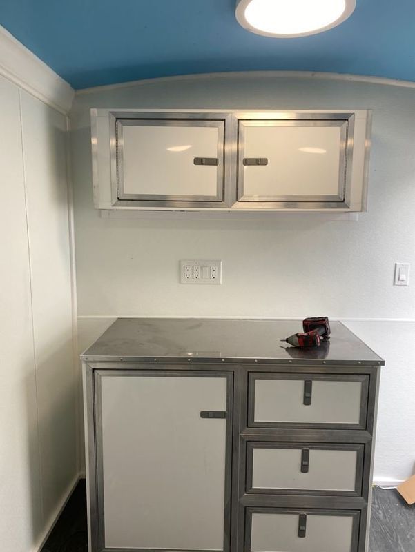 A white cabinet with drawers and a blue ceiling in a room.