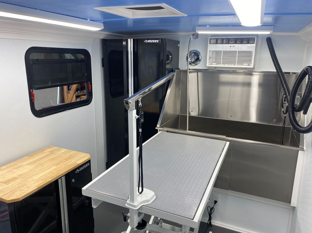 The inside of a dog grooming van with a table and a sink.