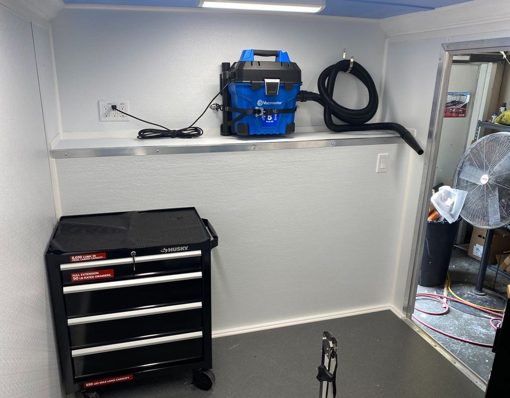 A room with a toolbox and a vacuum cleaner on the wall