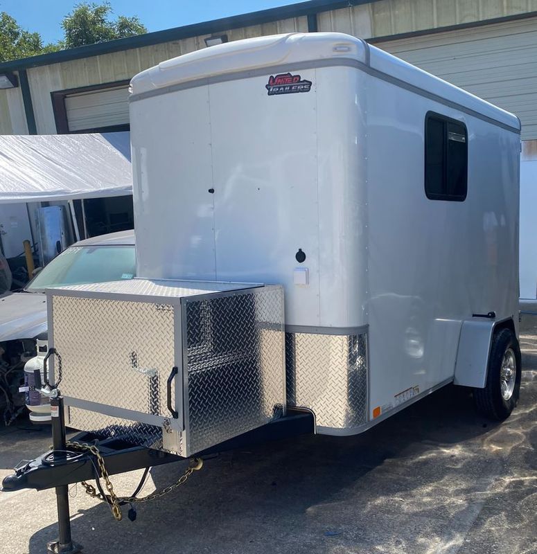 A white trailer is parked in front of a building