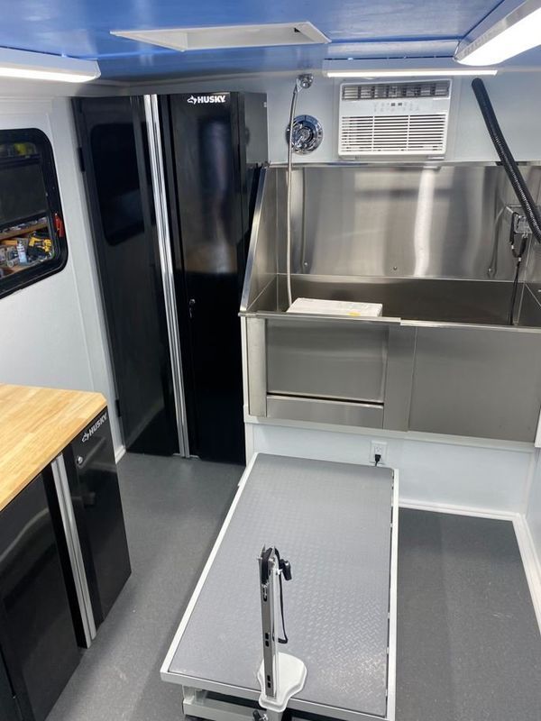 A dog grooming van with a stainless steel sink and a table.