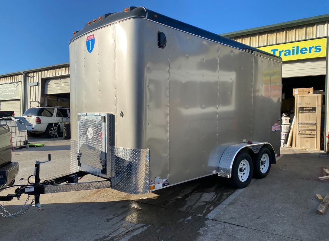 A trailer is parked in front of a trailers store.