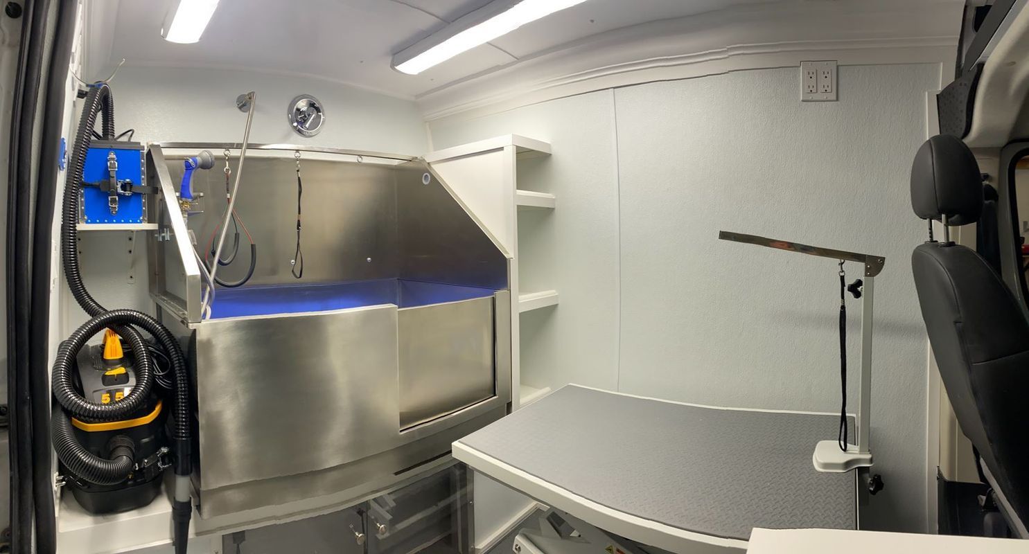 A dog grooming van with a stainless steel bathtub and a table.