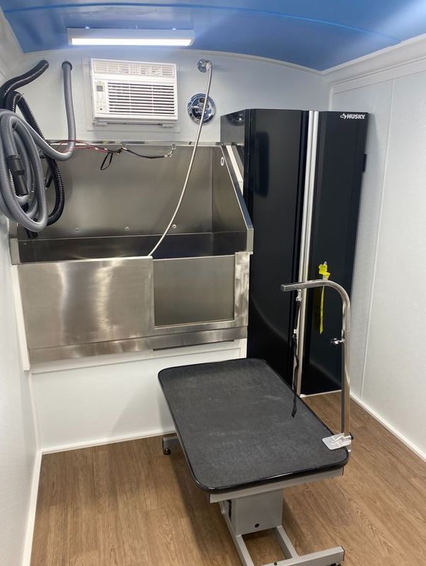 A room with a stainless steel sink and a black refrigerator.