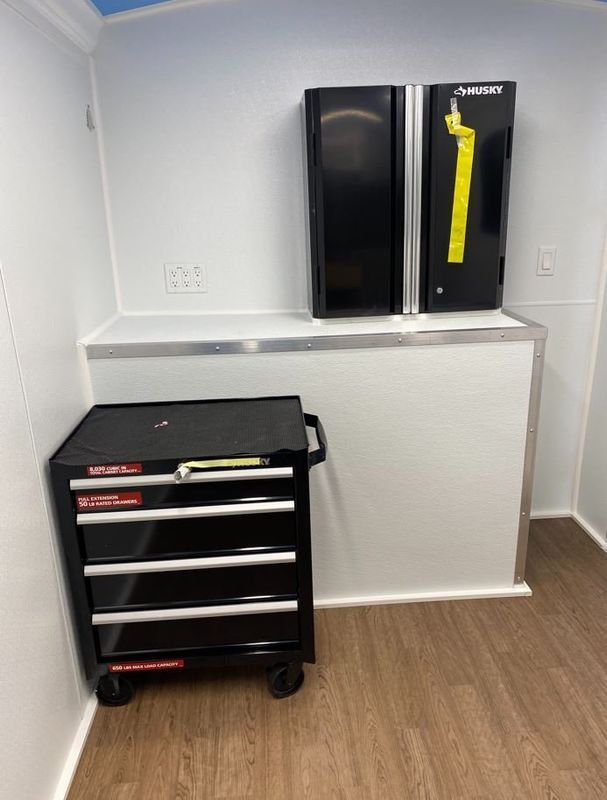 A black toolbox is sitting on a wooden floor in a room.