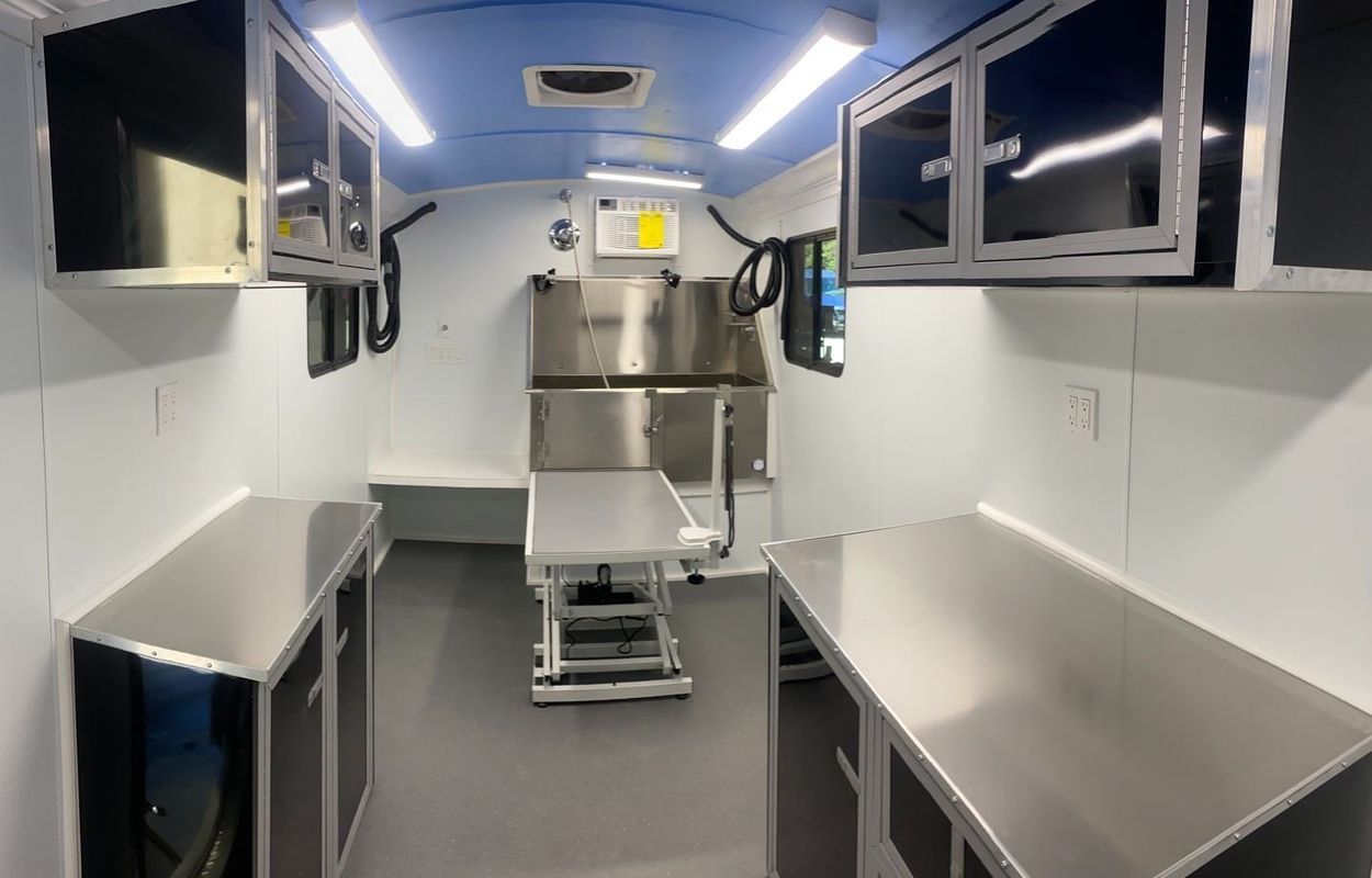 The inside of a van with stainless steel counter tops and a refrigerator.