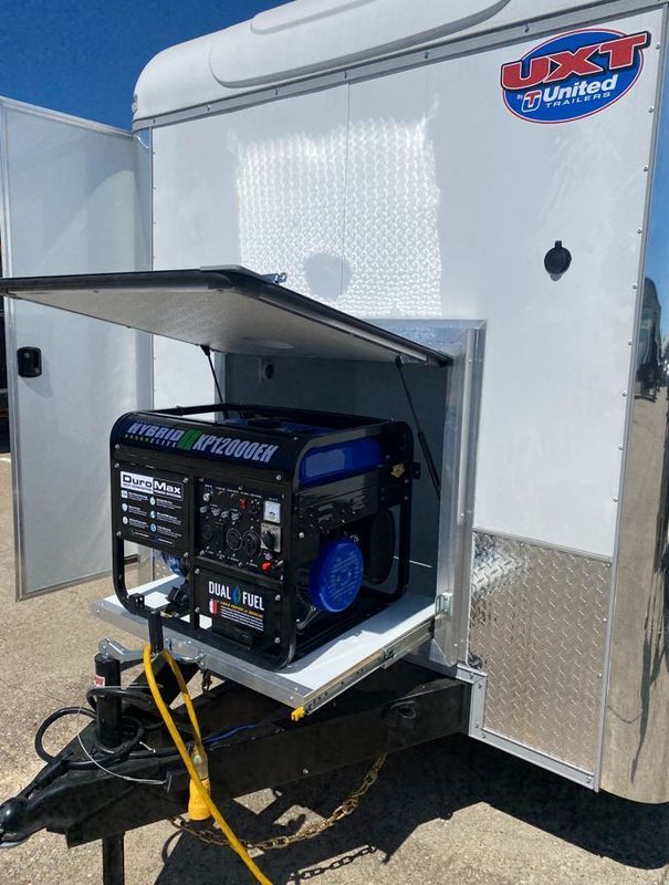 A generator is sitting inside of a trailer with the door open.