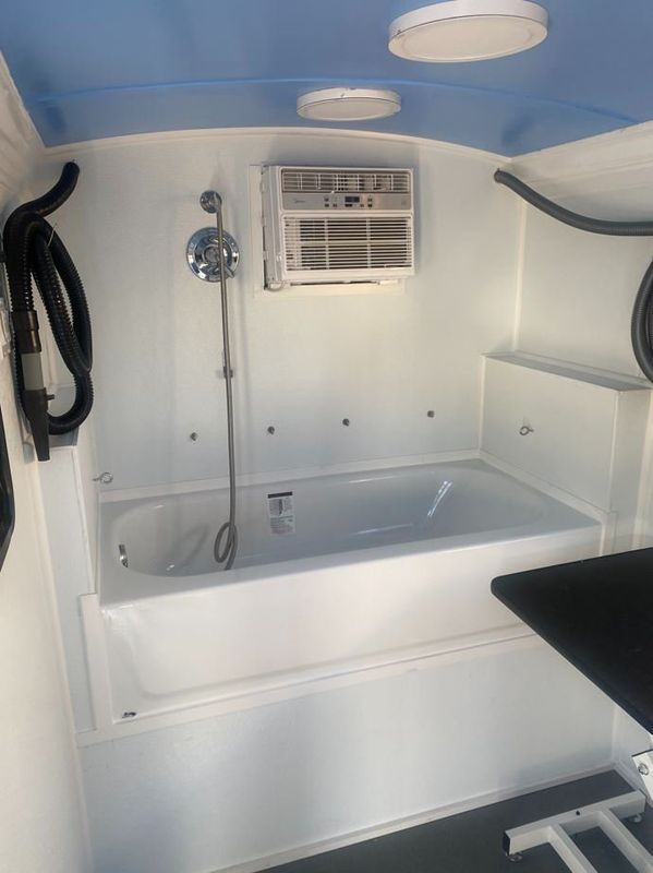 A bathroom with a bathtub , shower , and air conditioner.