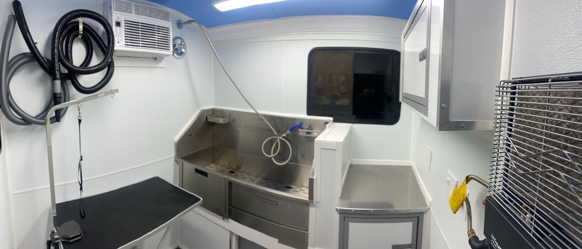 The inside of a dog grooming van with a sink and a table.