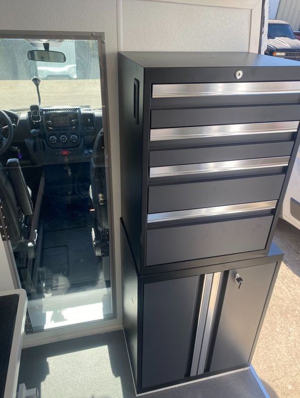 A black cabinet is stacked on top of another cabinet in a van.