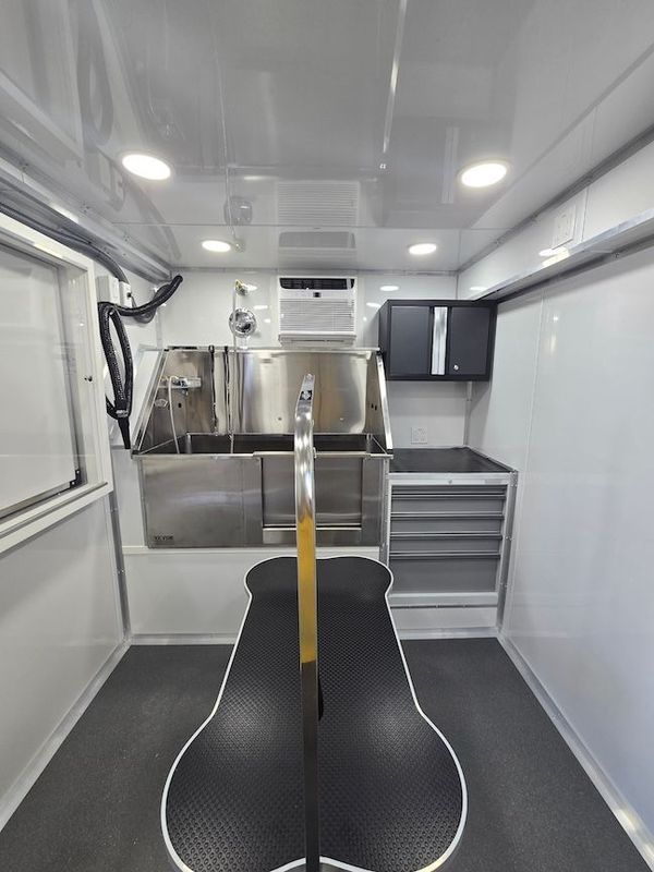 The inside of a dog grooming trailer with a stainless steel sink.