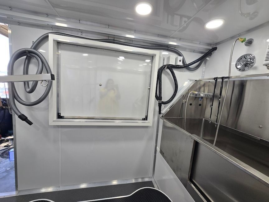 The inside of a dog grooming van with a vacuum hose hanging from the ceiling.