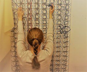 Artist mapping the circulation system on bed of mattress springs
