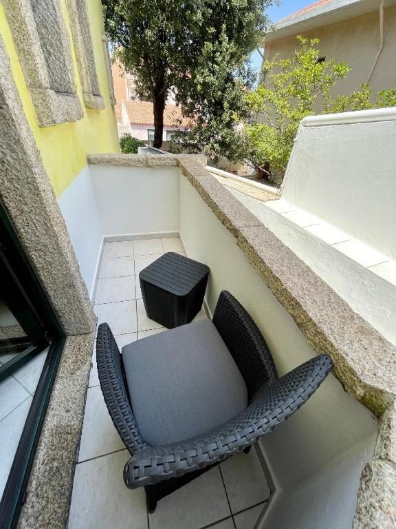 Una sedia di vimini è appoggiata su un balcone, accanto a una finestra.