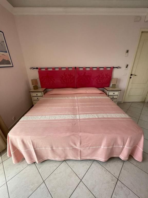 Un letto con una coperta rosa e una testiera rossa in una camera da letto.