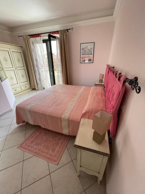 Una camera da letto con un letto, un comodino, una lampada e una finestra.