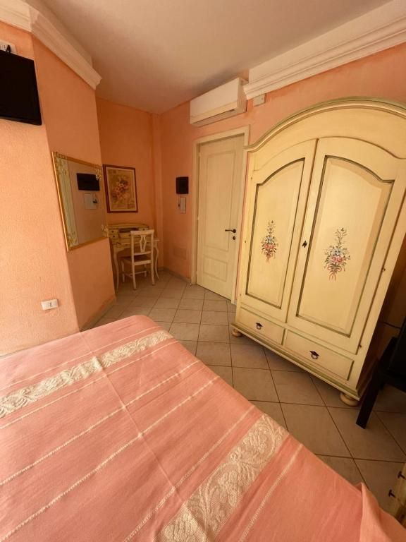 Una camera da letto con un letto rosa e un armadio bianco