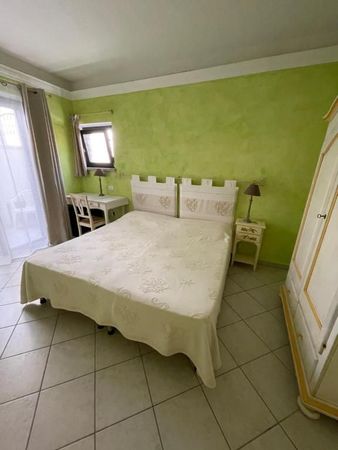 A bedroom with a bed, a desk, a bedside table, and a wardrobe.
