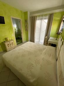 Una camera da letto con letto, comodino, televisione e porte scorrevoli in vetro.