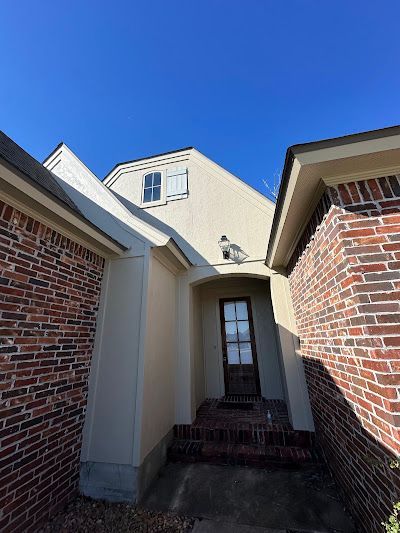 A white house with a brick wall and a door.
