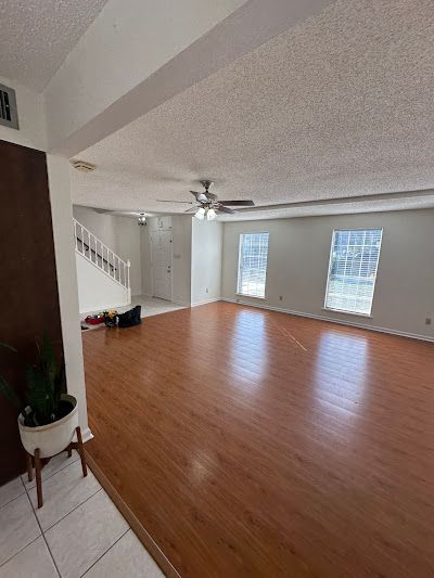A large empty living room with hardwood floors and a ceiling fan.