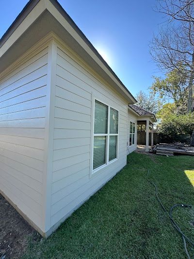 A white house with a lot of windows is sitting on top of a lush green lawn.