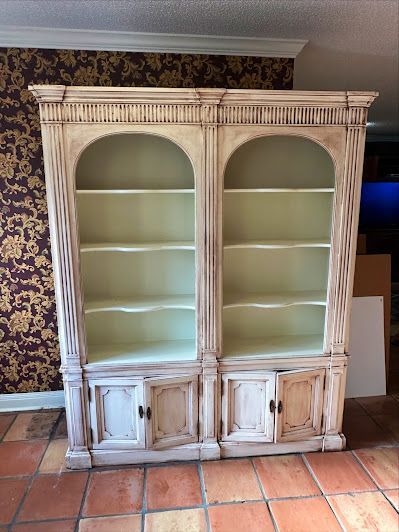A white bookcase is sitting on a tiled floor in a room.