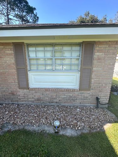 A brick house with a window and shutters on it.
