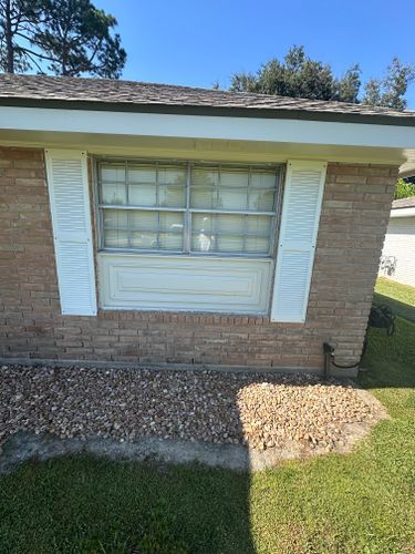 A brick house with a window and white shutters on it.