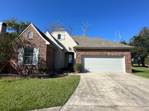 A brick house with a white garage door and a driveway.
