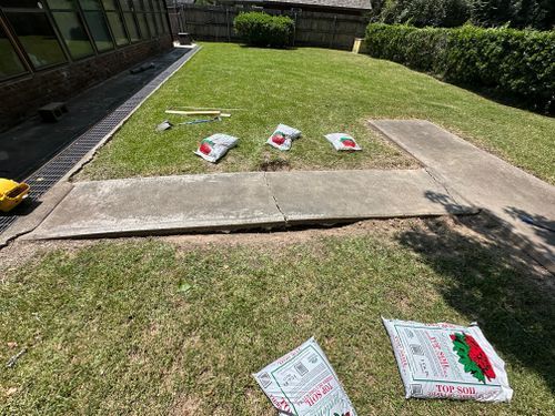 A concrete walkway is being built in a backyard.
